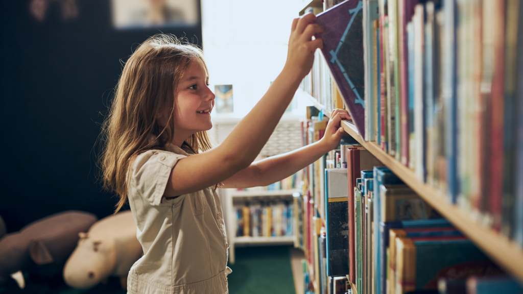 Child choosing books at a local library summer reading program