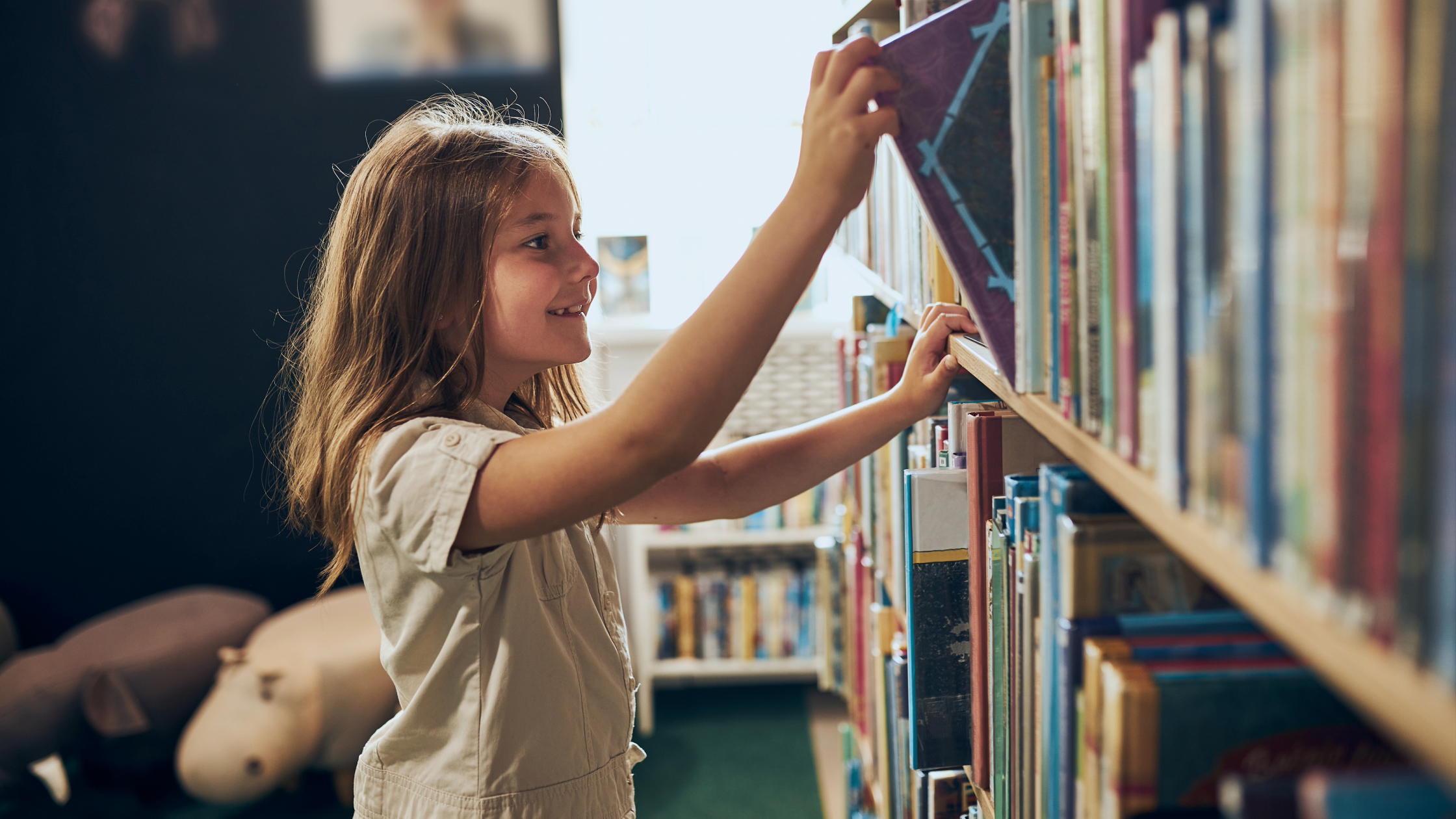 Young girl picking book from the library